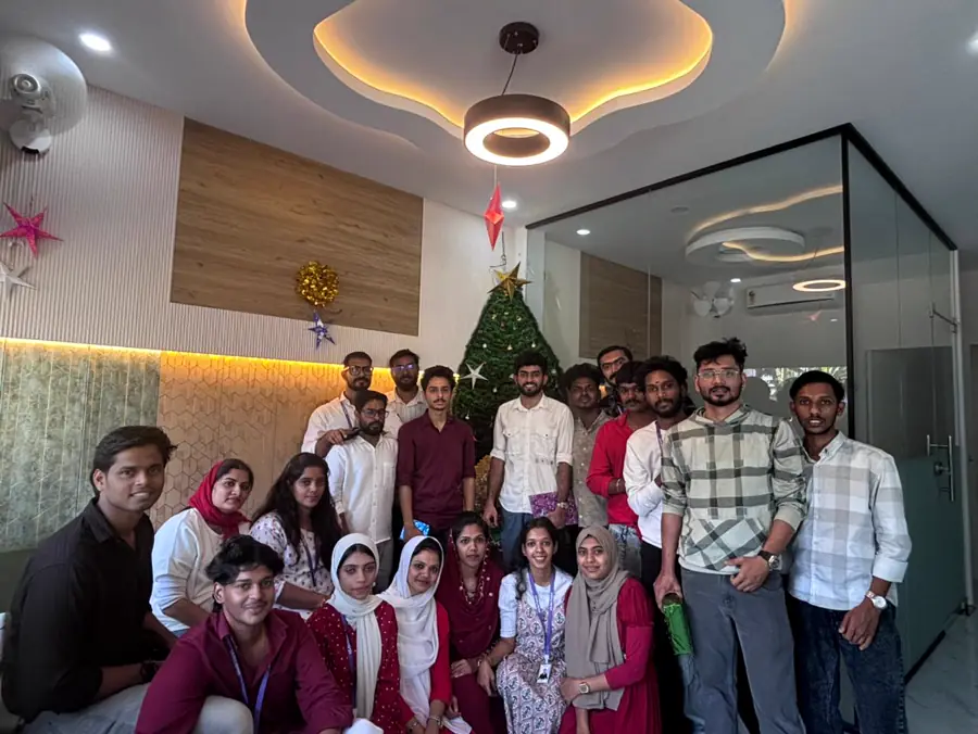 Team members beside the Christmas tree in the office